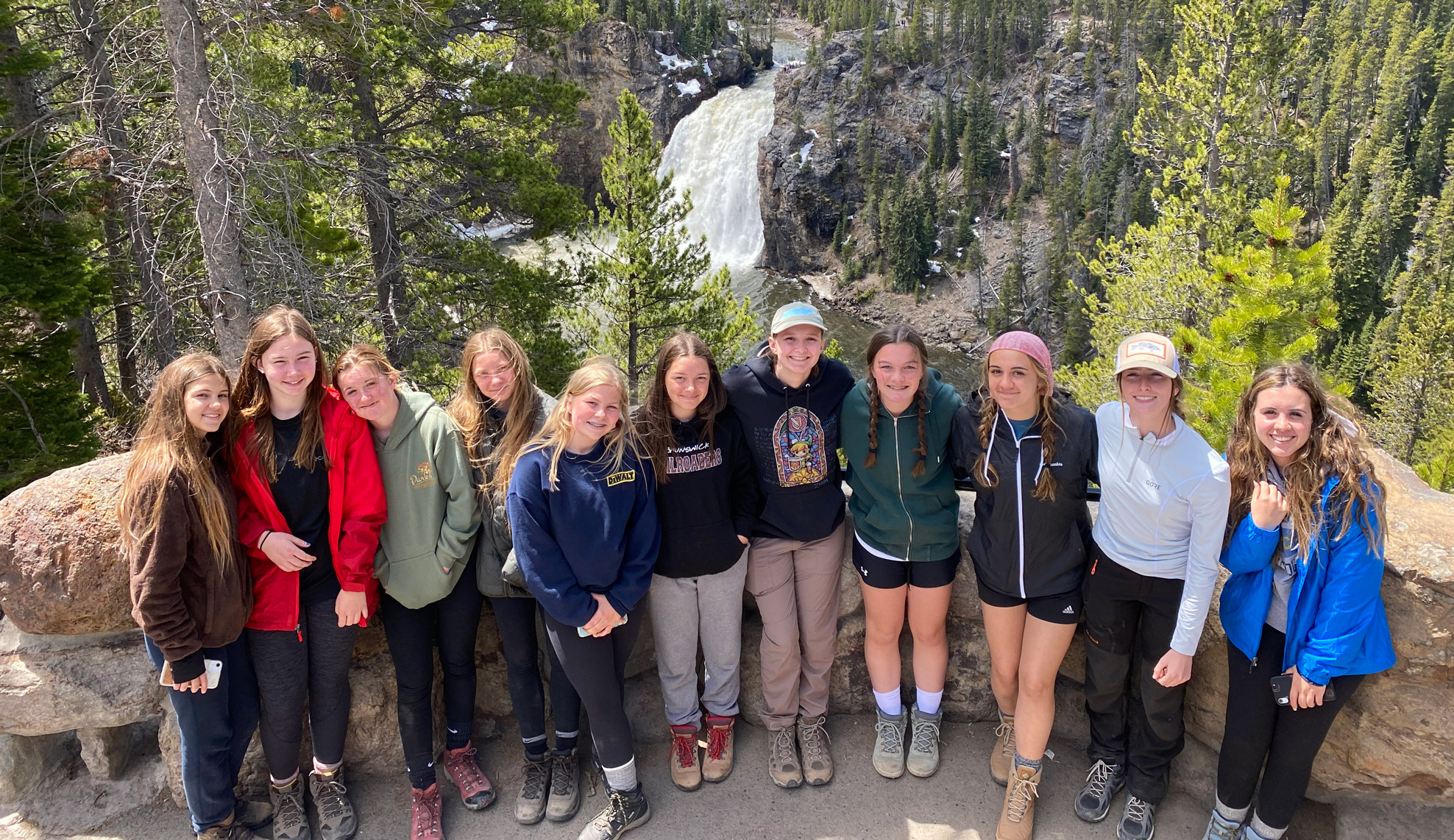 youth educational adventures group posing and smiling above a large waterfall